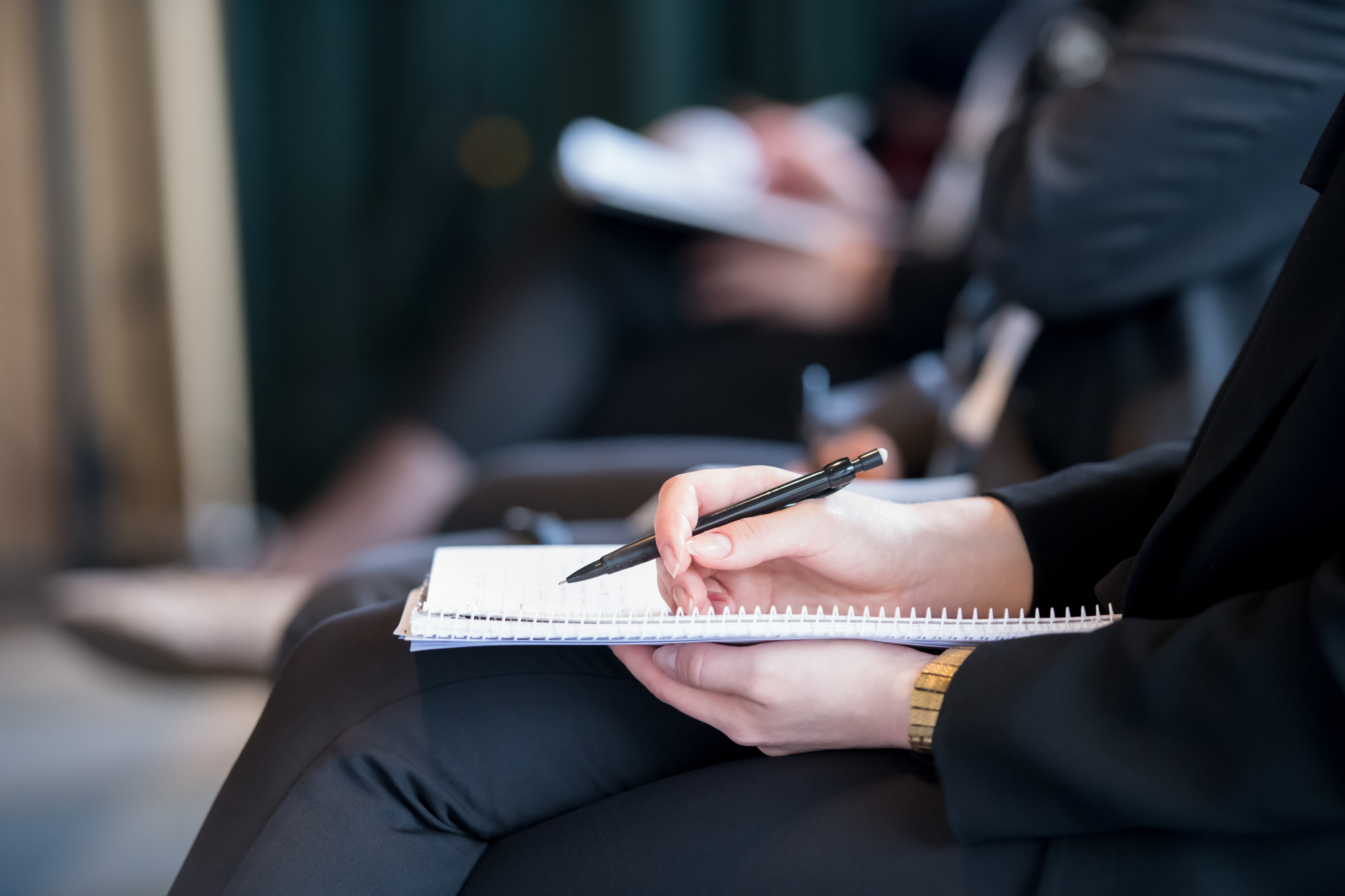 closeup shot of business people hands using pen while taking notes on education training during business seminar at modern conference room