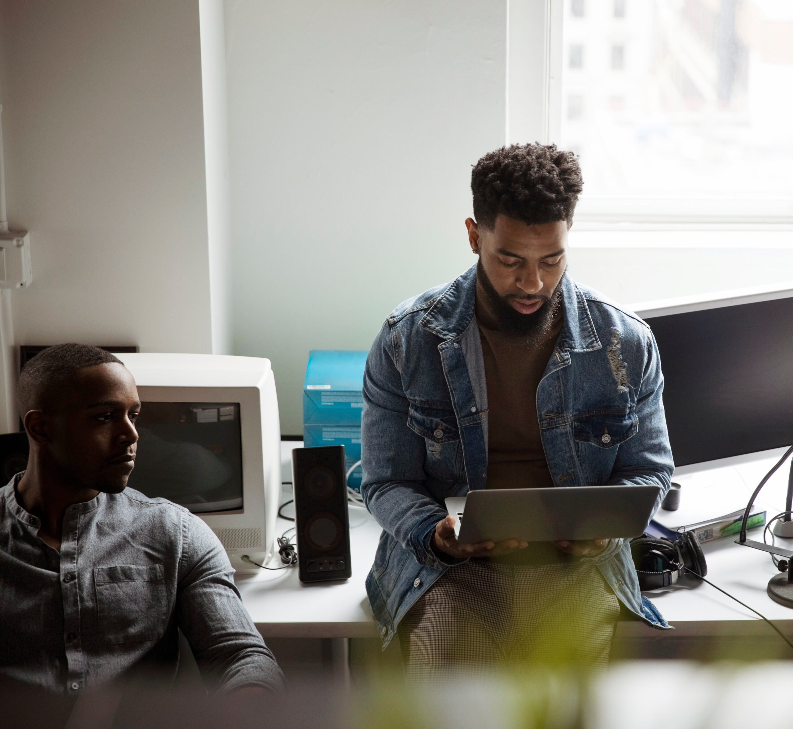 High angle view of businessman using laptop computer while standing by colleague against window in office