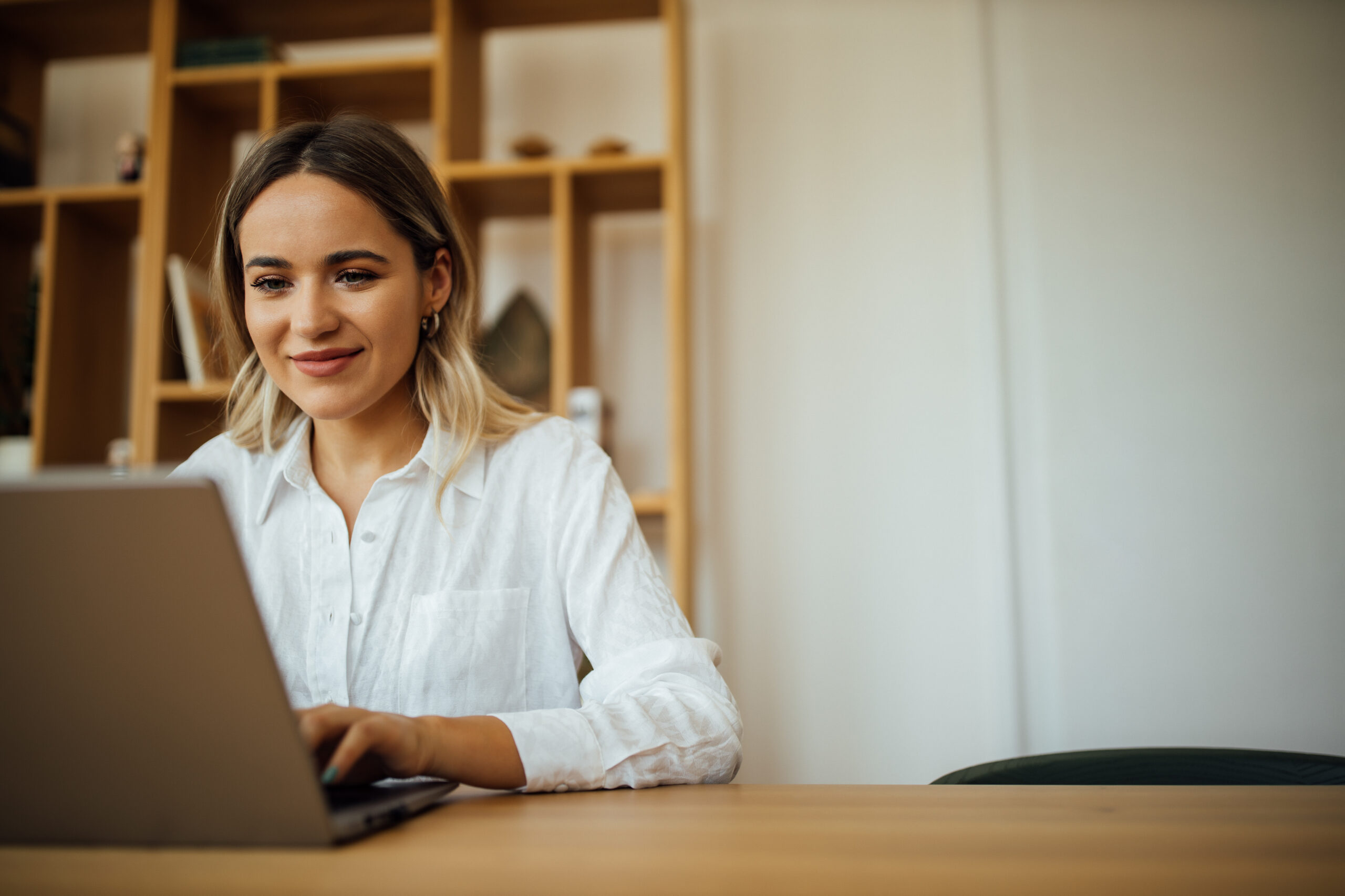 Young beautiful woman working on laptop at home office, copy space, portrait.